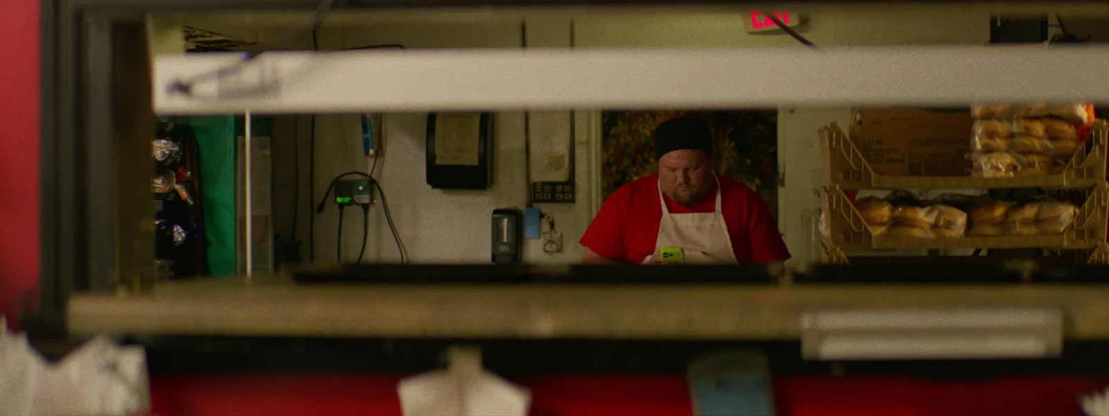 A cook in a white apron framed through the kitchen pass of a diner